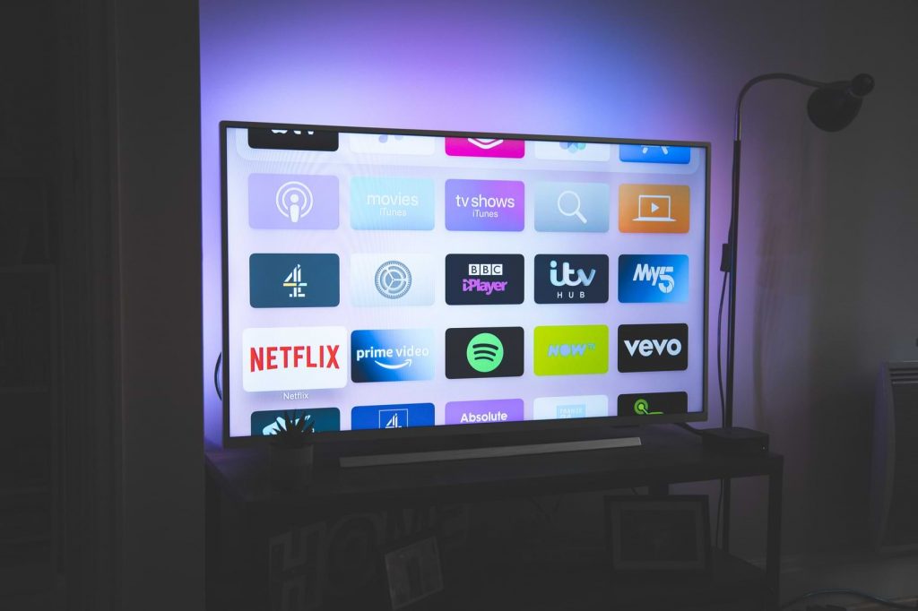 A Smart TV displays various apps like Netflix, Spotify, iTV Hub and more.