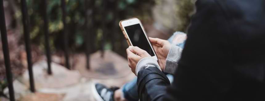 A person sits and browses through their smartphone, after learning how to choose a cell phone plan.